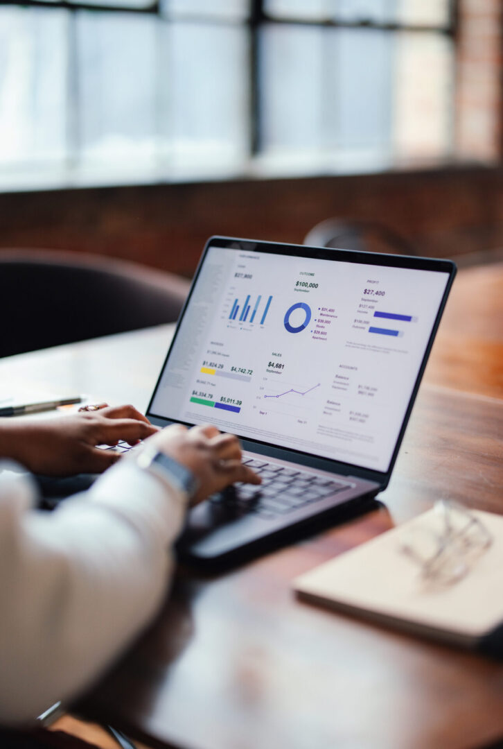 Hands typing on laptop with graphs visible