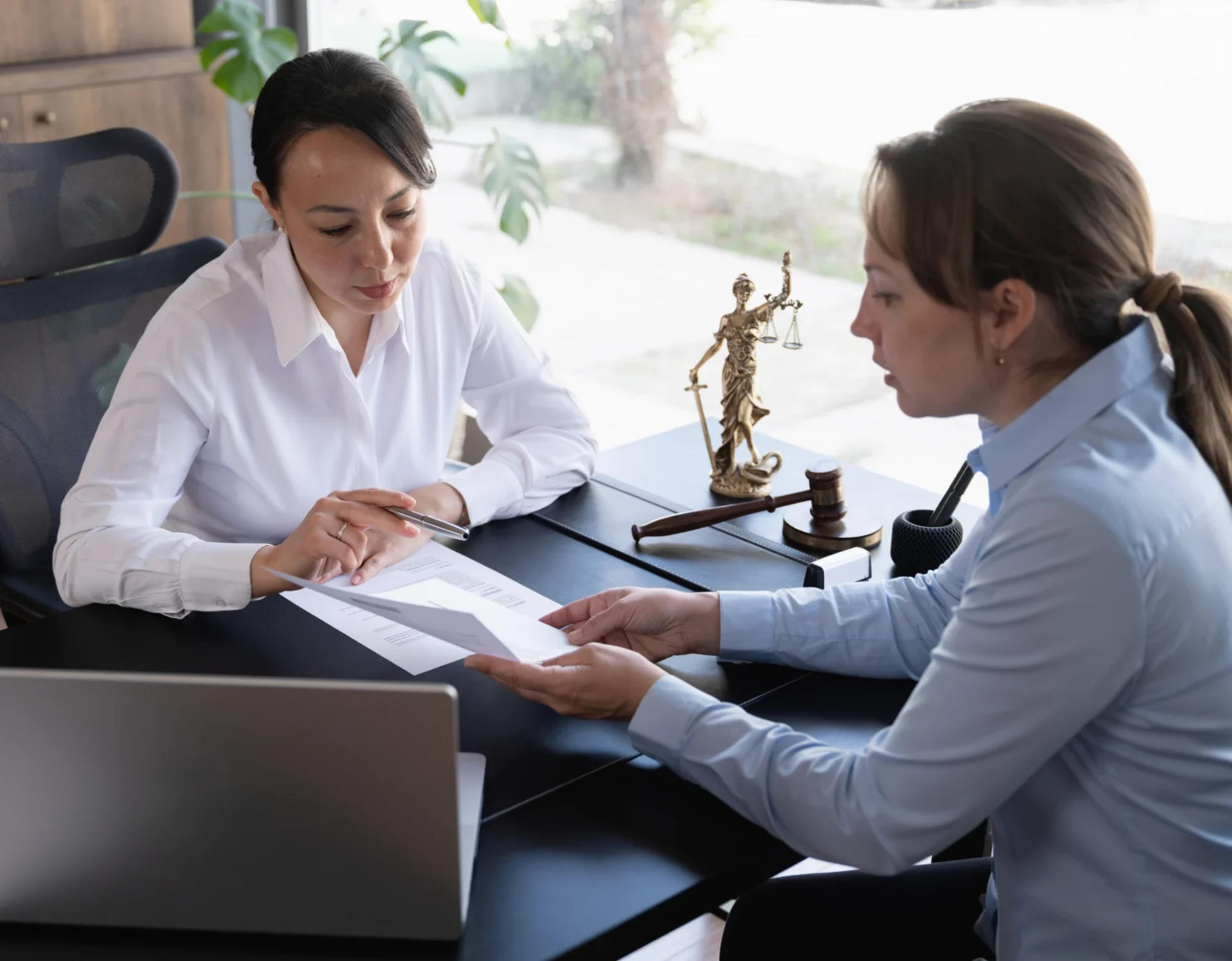 Two women discussing documents in office